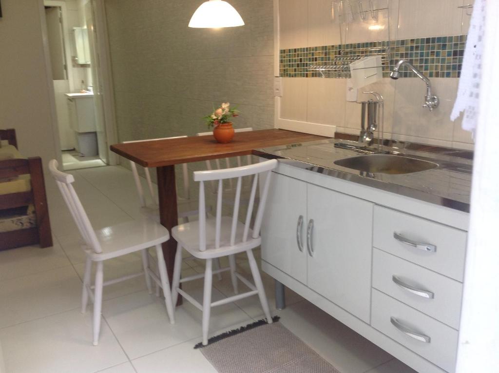 a kitchen with a sink and a table and chairs at Loft e Vila da Praia Studios Ilha Grande in Abraão