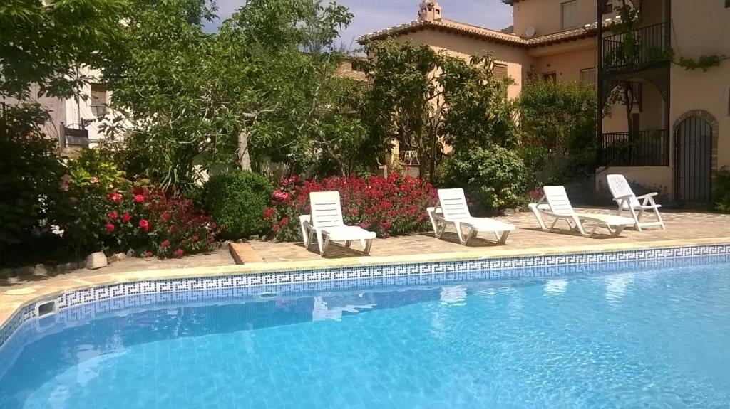 una piscina con sillas y una casa en Casa Tia Maria, Acequias, en Acequias