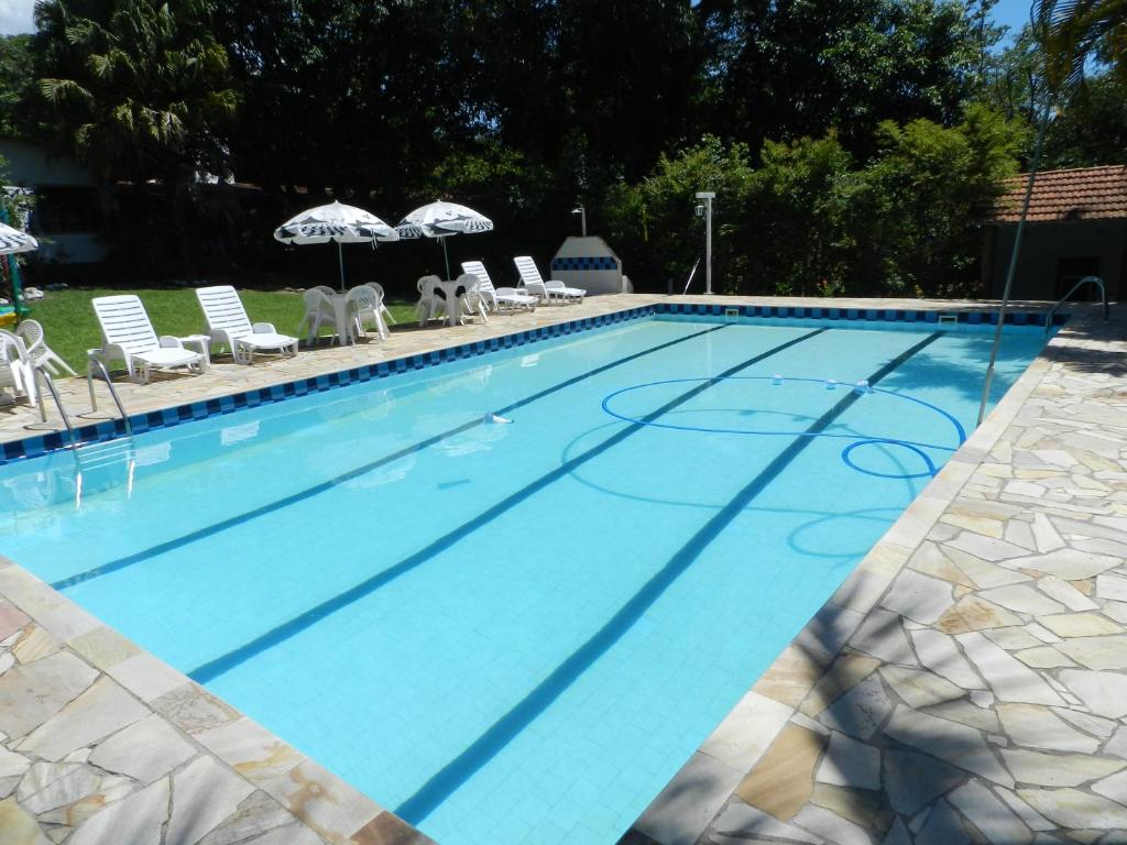 a large blue swimming pool with chairs and umbrellas at Pousada Ypê Amarelo in Itatiaia