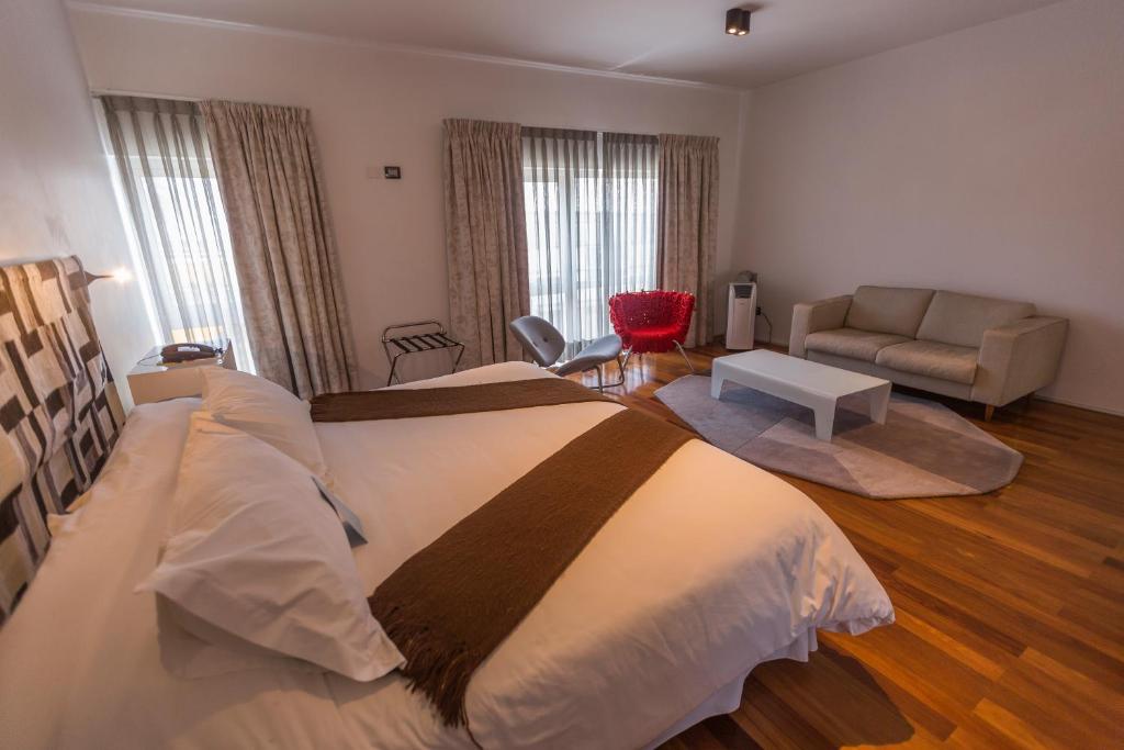 um quarto com uma cama grande e um sofá em Aruma Hotel Boutique em Arica