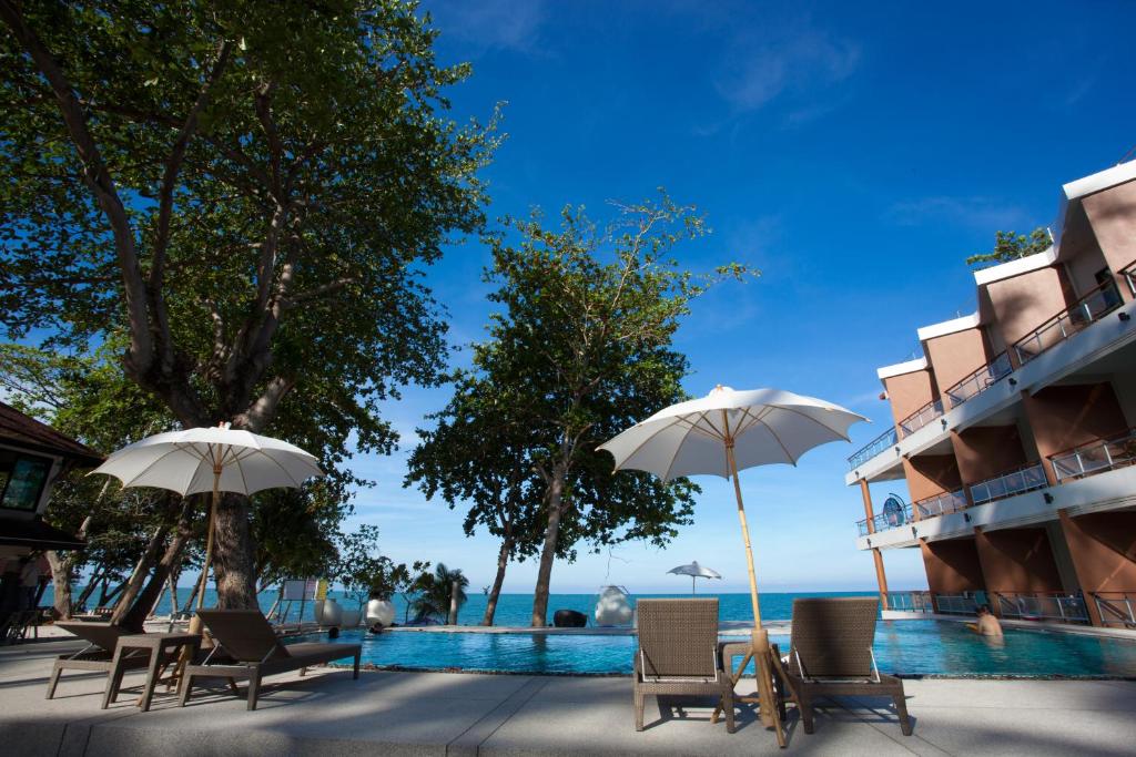 eine Gruppe von Stühlen und Sonnenschirmen neben einem Pool in der Unterkunft Prasarnsook Villa Beach Resort in Sichon