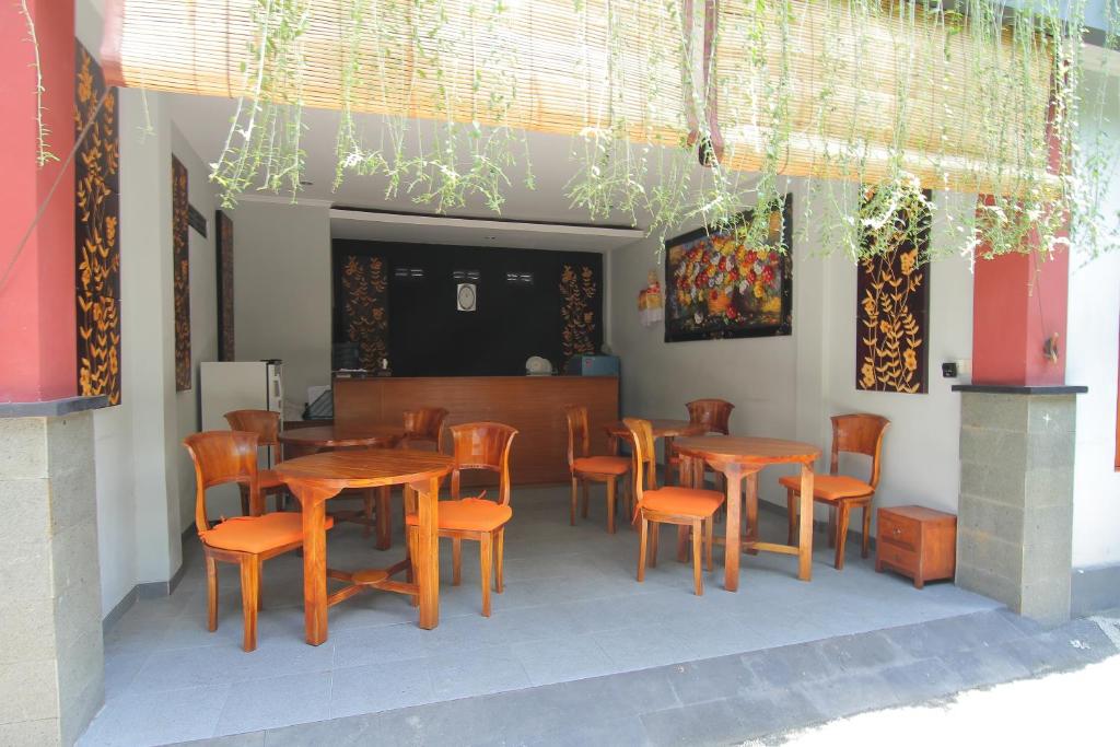 un restaurante con mesas de madera y sillas naranjas en Bubu Inn, en Ubud