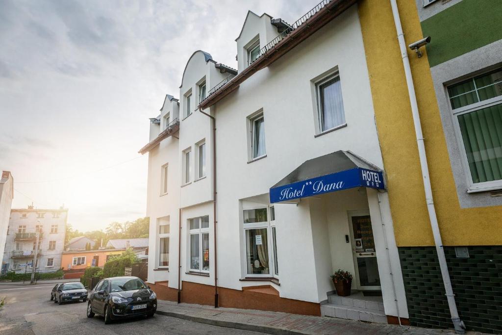 a white building with a blue sign on it at Hotel Dana in Bytów