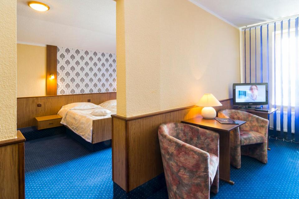 シュチェチンにあるHotel Victoriaのベッド、デスク、椅子が備わるホテルルームです。