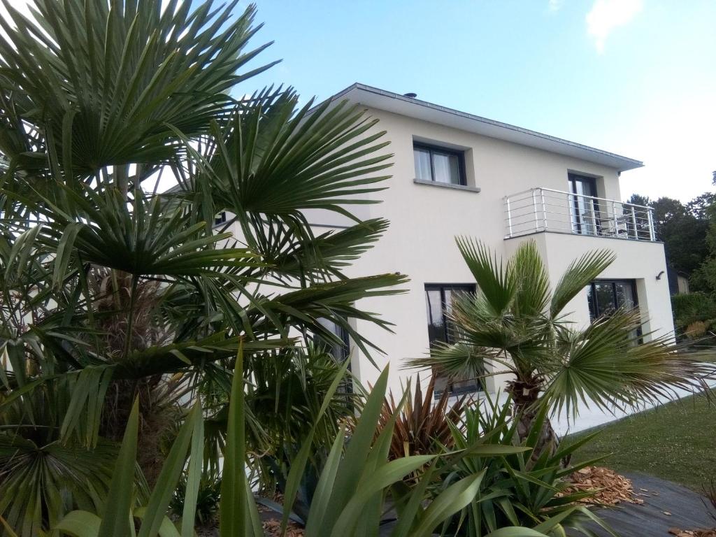 une maison blanche avec des palmiers devant elle dans l'établissement Chambre d'hôtes Les Bruyères, à Bruc-sur-Aff