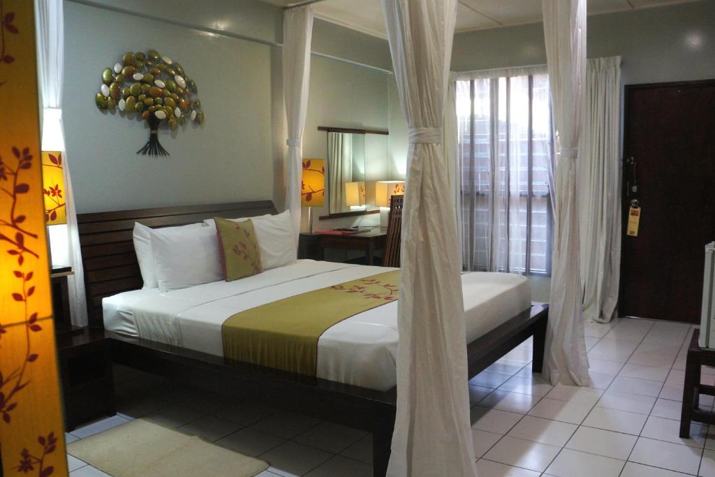 a bedroom with a bed and a desk in a room at Raintree Lodge in Port Moresby