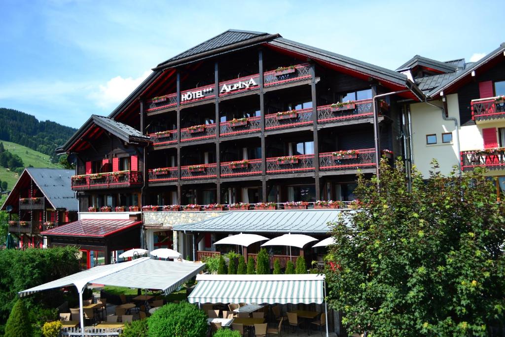 a large building with tables and chairs in front of it at Hôtel Alpina &amp; SPA in Les Gets