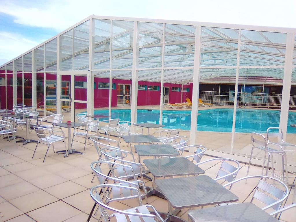 a patio with tables and chairs next to a swimming pool at Eté indien-hôtellerie de plein air in Wimereux