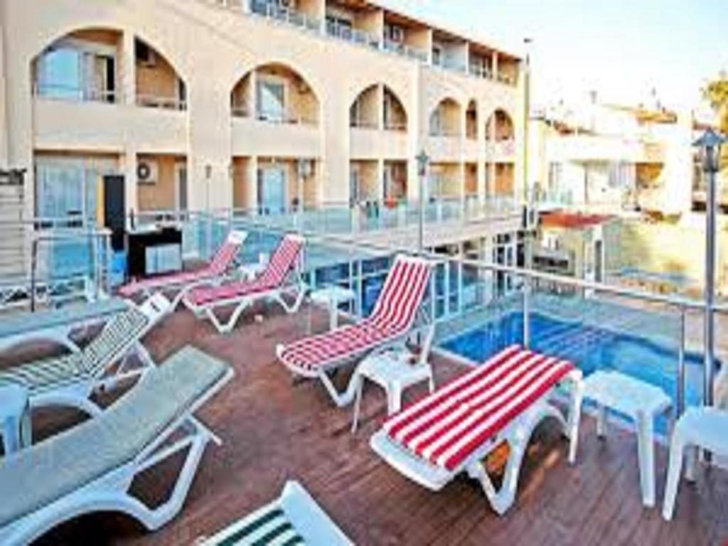 a balcony with lounge chairs and a pool on a building at Ucem Hotel Golden Sea in Altınoluk
