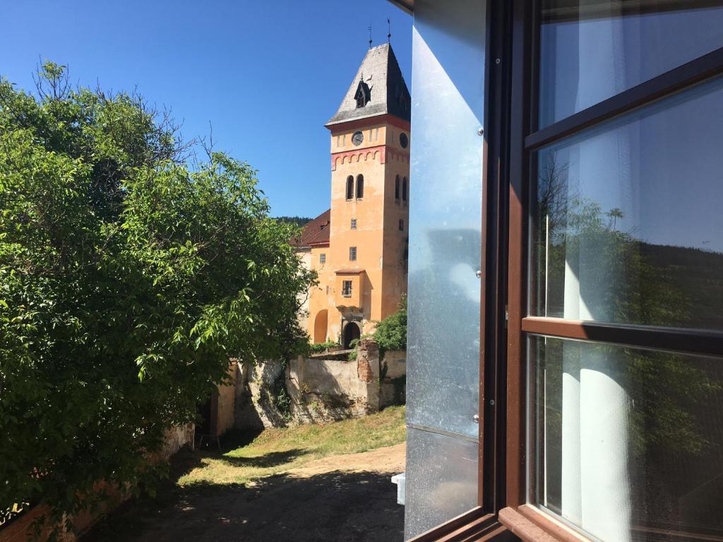 a window view of a building with a clock tower at Apartmány Zámek - Vimperk in Vimperk