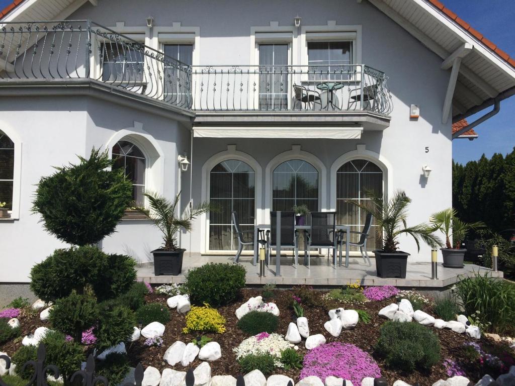 ein Haus mit einem Balkon und einem Garten mit Blumen in der Unterkunft Judit Vendégház in Bük