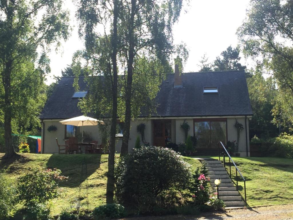 a small house with a table and an umbrella at Daedalus Bed & Breakfast in Muir of Ord