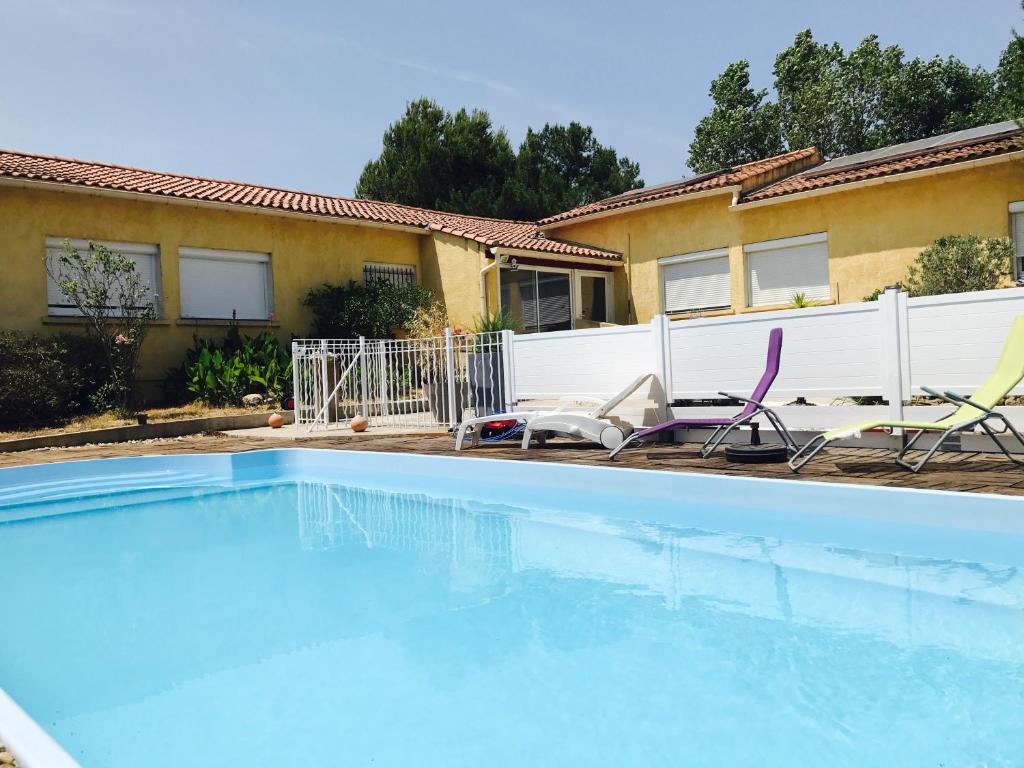- une piscine avec 2 chaises et une maison dans l'établissement Chambre d'hôtes Costa Belle, à Lunel-Viel
