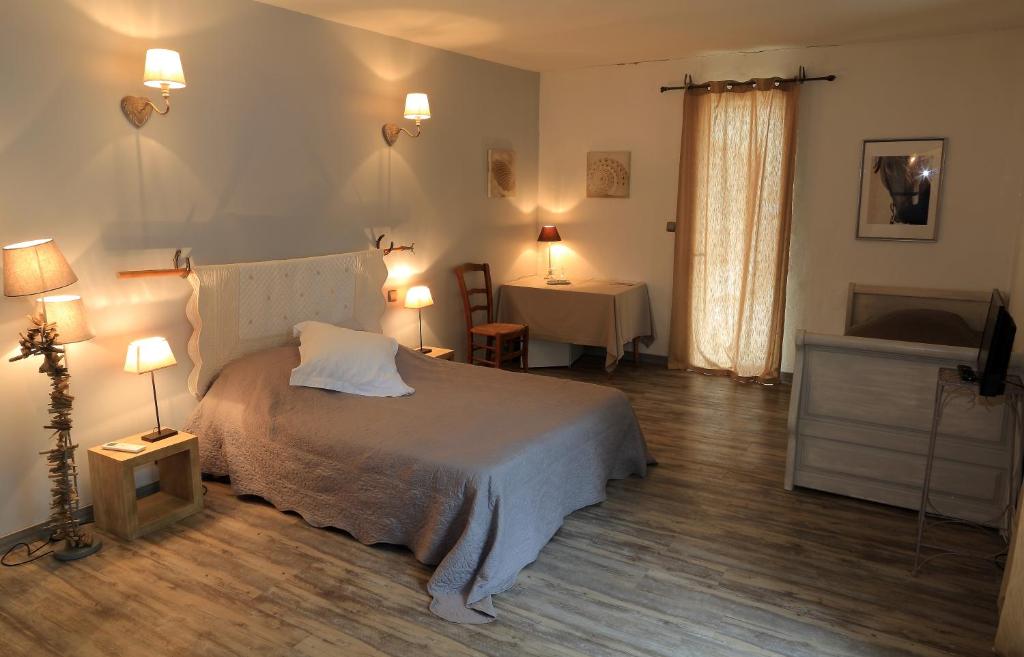 サン・ジルにあるMas d'Auzièresのベッドルーム1室(ベッド1台、ランプ2つ、テーブル付)