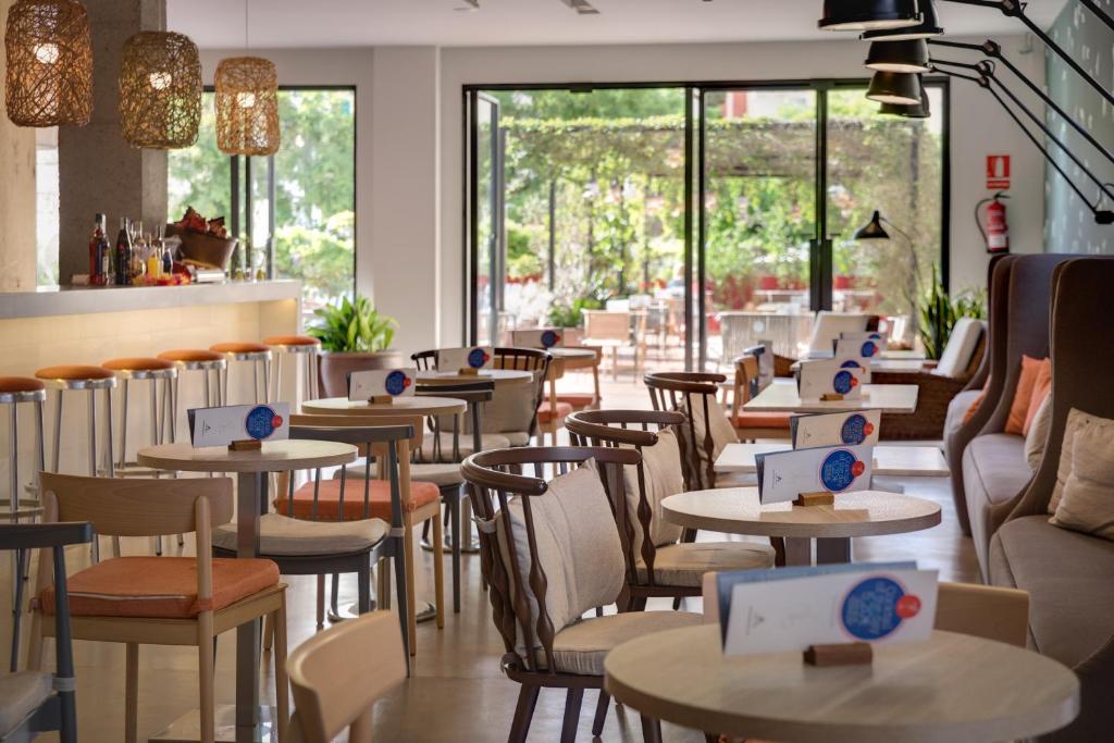 a restaurant with tables and chairs and windows at AQUA Hotel Bertran Park in Lloret de Mar