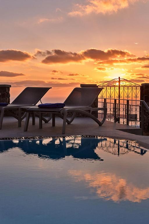 two picnic tables sitting next to a pool of water at Villa Dakoronia in Fira