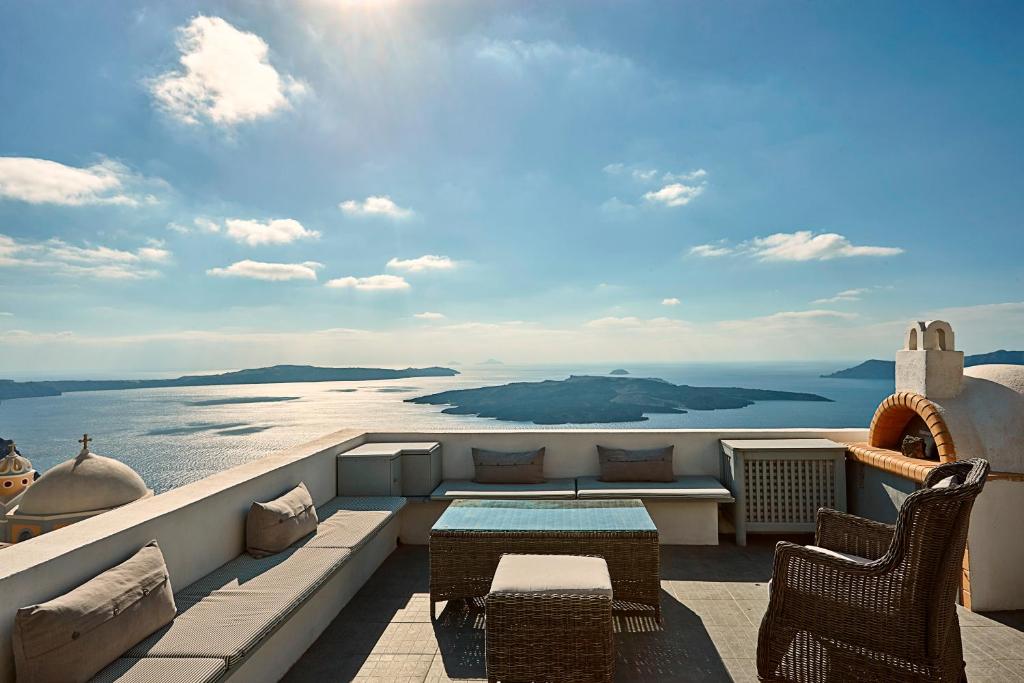 balcón con mesa, sillas y vistas al océano en Villa Dakoronia, en Fira