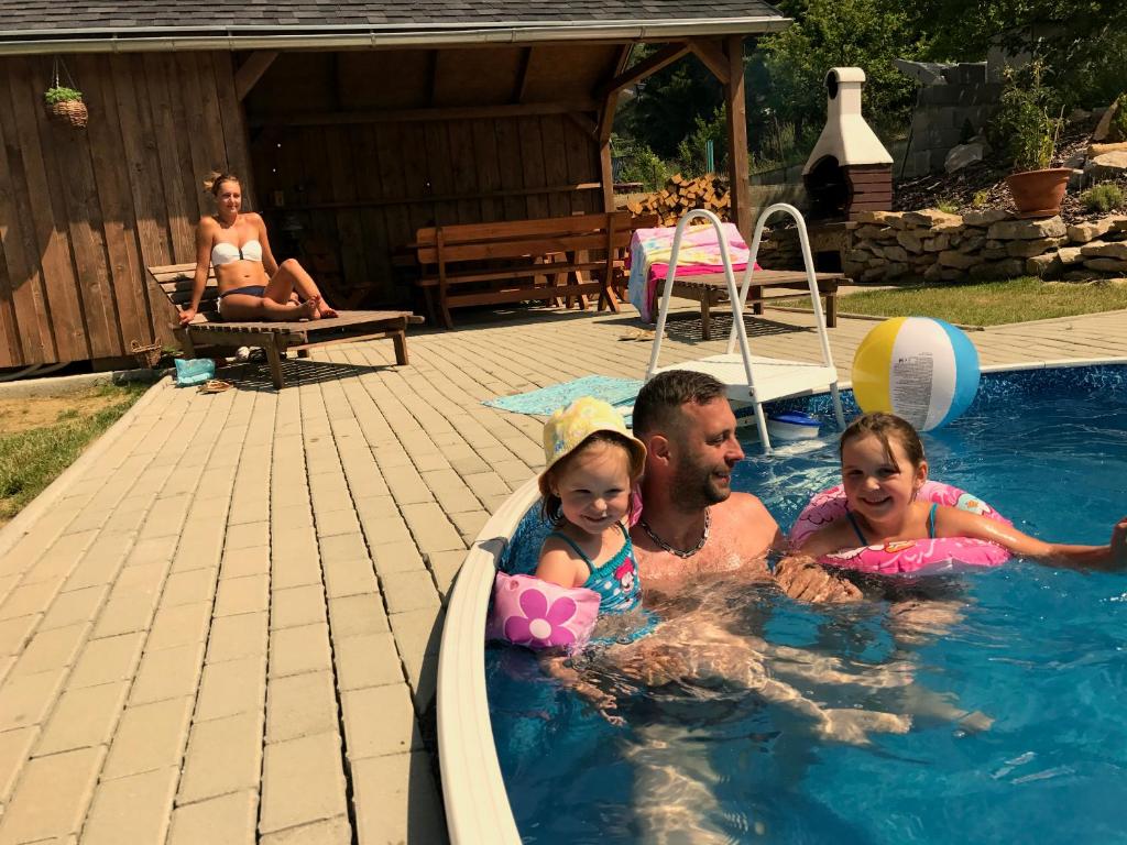 a man and two children in a swimming pool at Hekel's privat in Závažná Poruba