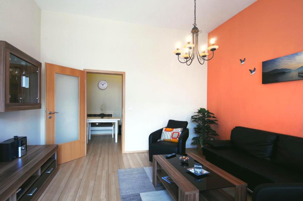 ein Wohnzimmer mit einem schwarzen Sofa und einer orangefarbenen Wand in der Unterkunft Ferienwohnung Warnemünde - L (N) in Warnemünde