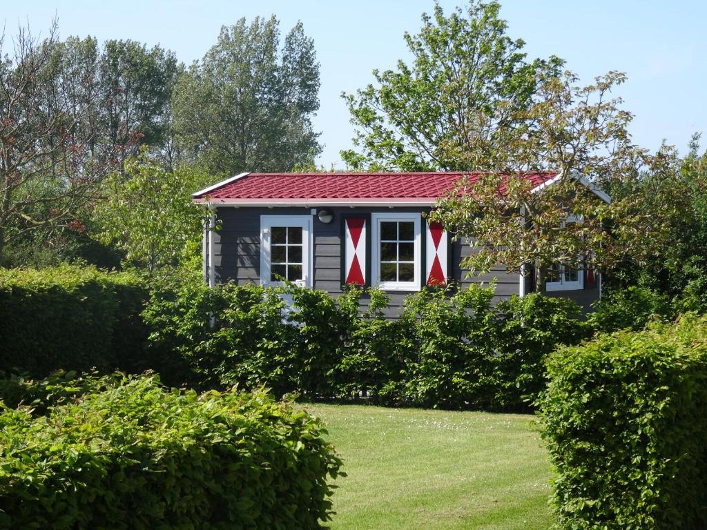 een klein huis met een rood dak en een tuin bij zeeuwse chalet voor 2 personen in Serooskerke