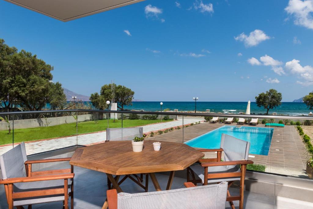 a table and chairs on a balcony with a view of the ocean at Niovi Seaside Suites in Kissamos