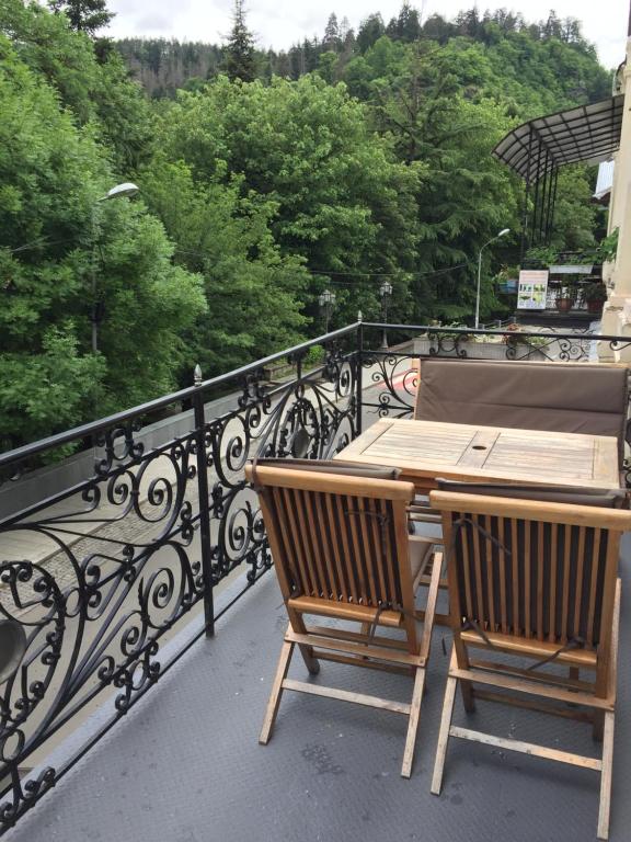 a balcony with a wooden table and chairs on a balcony at R and B in Borjomi