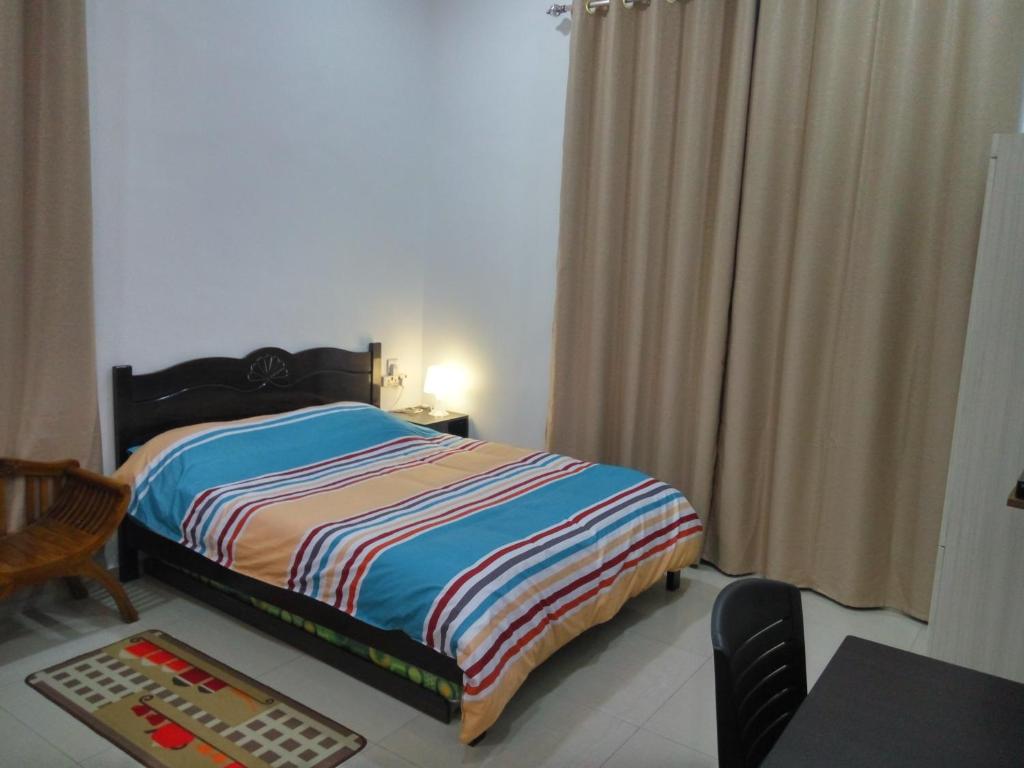 a bedroom with a bed and a table and a chair at H2O Apartment in Cameron Highlands