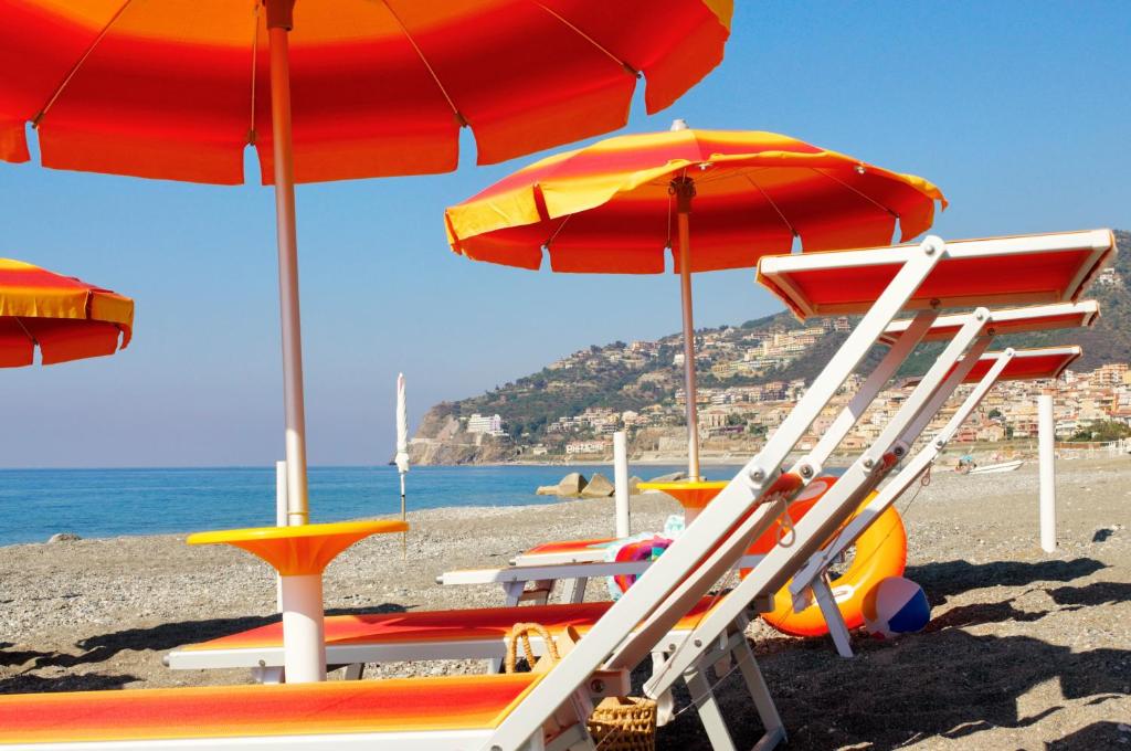 un gruppo di sedie a sdraio e ombrelloni sulla spiaggia di Camping Villaggio Calanovella a Piraino