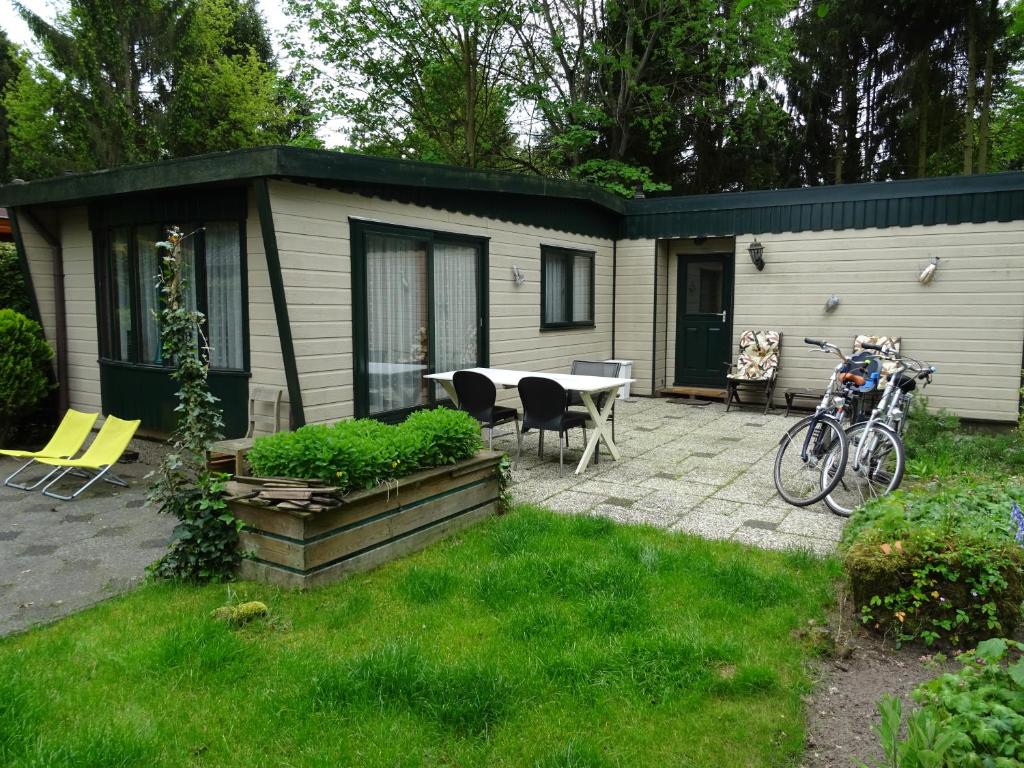 una pequeña casa con una mesa y sillas en un patio en Wonderful place on a quiet spot in the middle of the Netherlands, en Putten