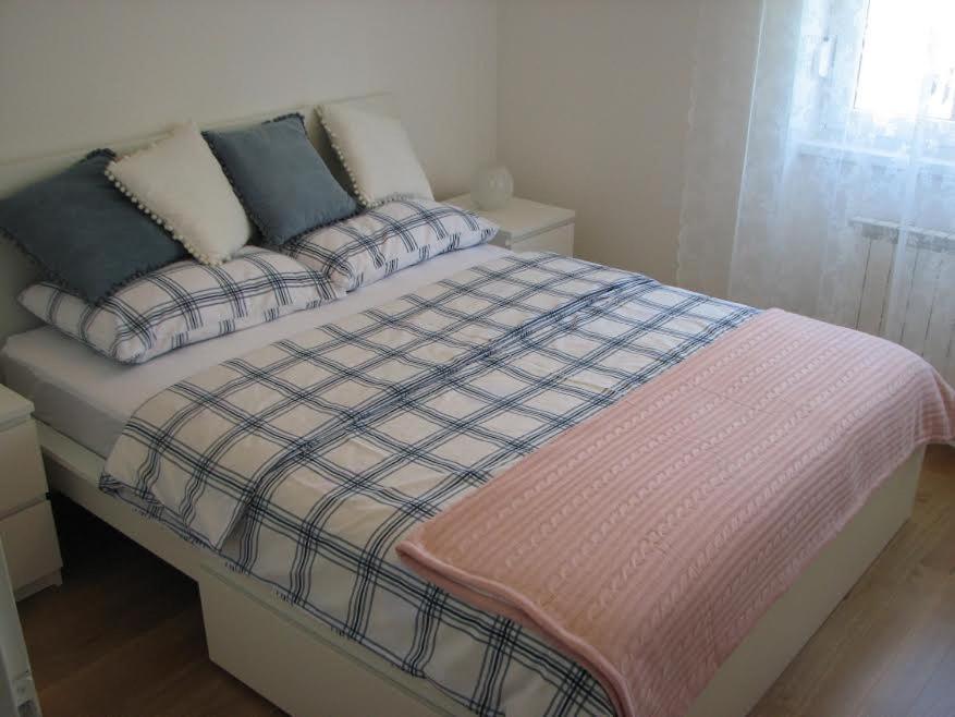 a bed with a plaid blanket and pillows on it at Sweet home in Plitvička Jezera