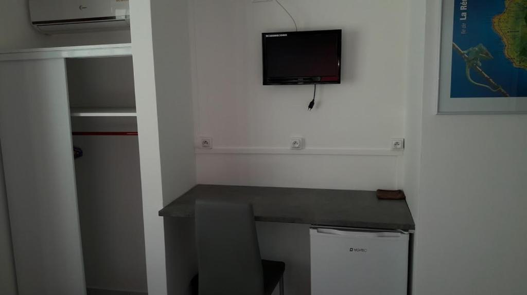 a room with a desk and a tv on the wall at Hôtel Du Centre in Saint-Denis
