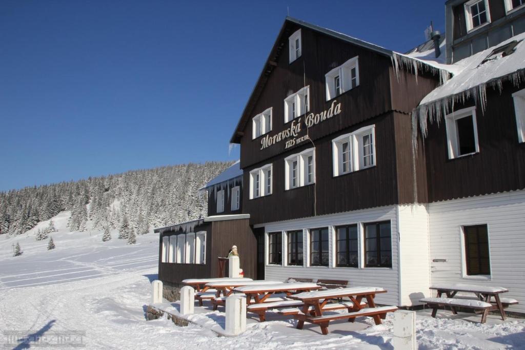 a large building with picnic tables in the snow at Moravská Bouda in Špindlerův Mlýn