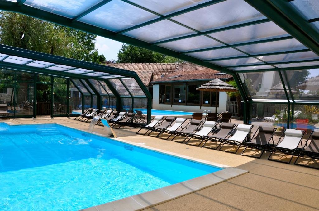 una piscina con sedie a sdraio e ombrellone di Caravaning Les Tourterelles a Rang-du-Fliers