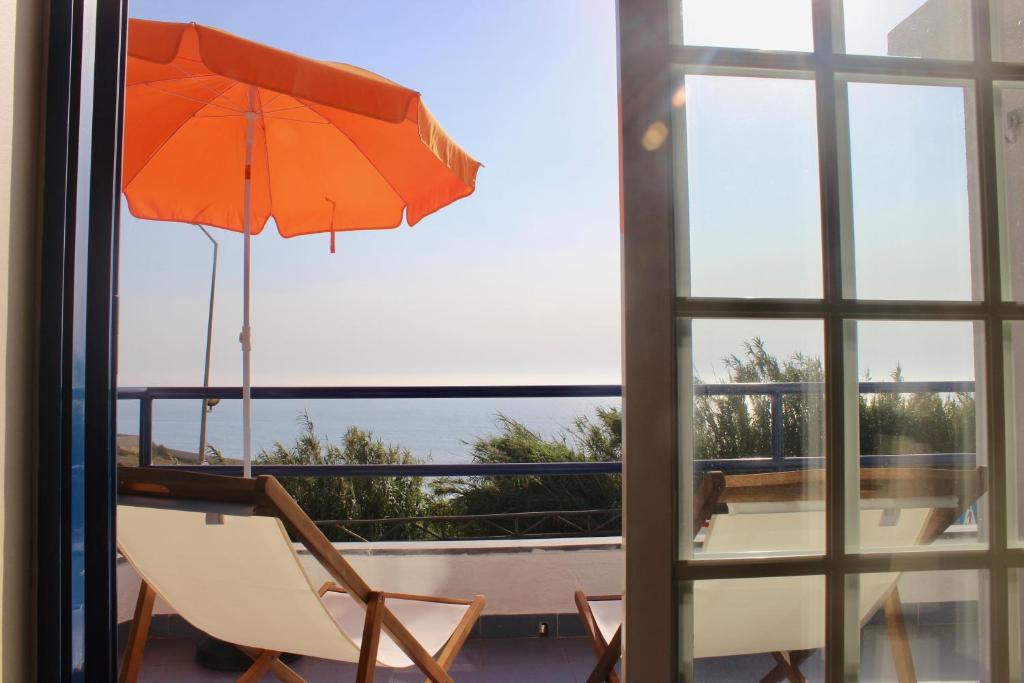 エリセイラにあるCasa do Sulのテーブルと椅子の横に座るオレンジの傘