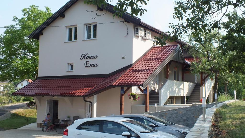 een wit huis met een auto ervoor geparkeerd bij Guest house Ema in Grabovac
