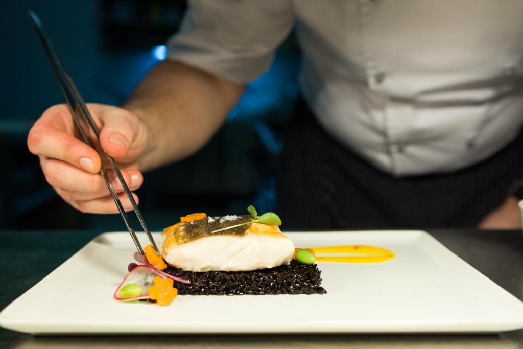 a person eating a piece of food on a plate at Alchymist Grand Hotel and Spa - Preferred Hotels & Resorts in Prague