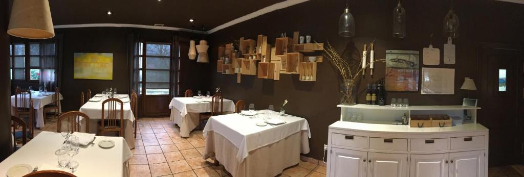 a restaurant with white tables and chairs and chandeliers at Zezilionea in Olaberría