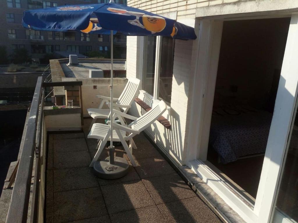 an umbrella and two chairs on a balcony at The coolest baby penthouse in Oostende in Ostend
