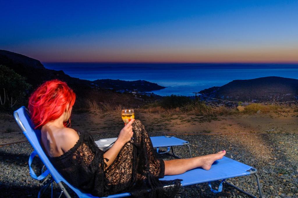 キニオンにあるVoulias Αpartmentsの椅子に座ってワインを飲む女性