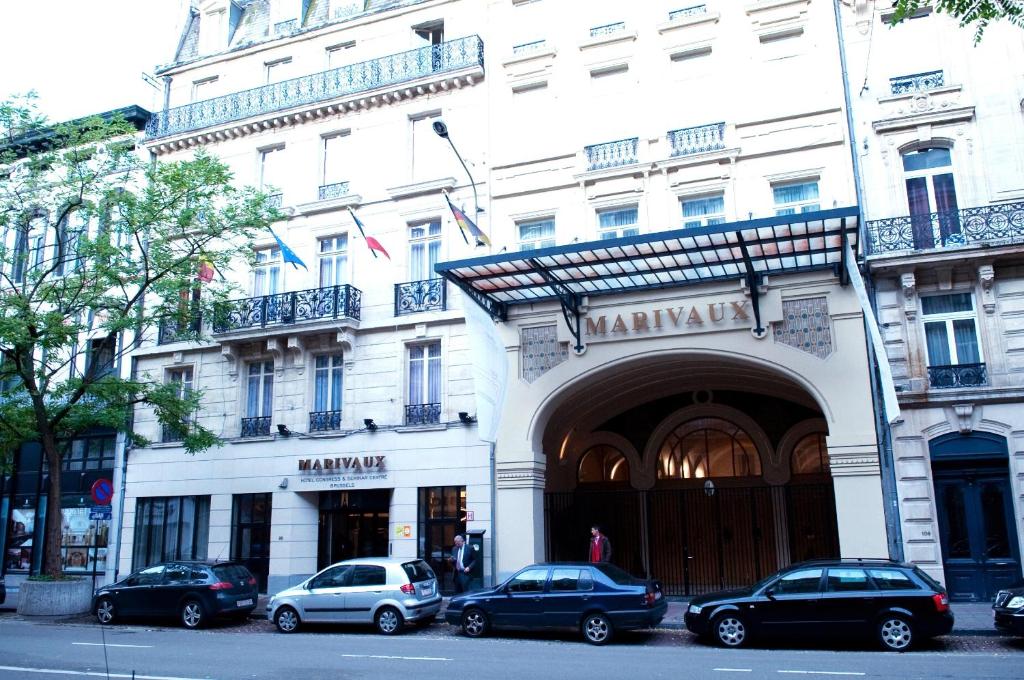 een groot wit gebouw met auto's geparkeerd voor het bij Marivaux Hotel in Brussel