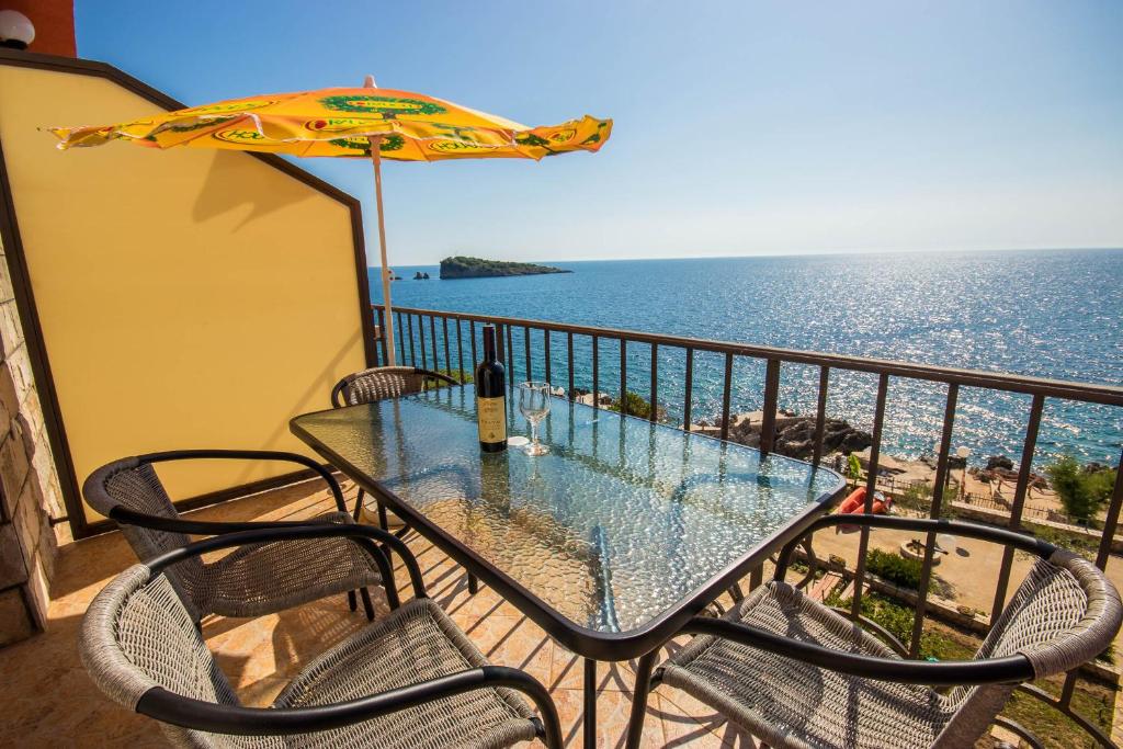 een tafel en stoelen op een balkon met uitzicht op de oceaan bij Apartments Posejdon in Utjeha