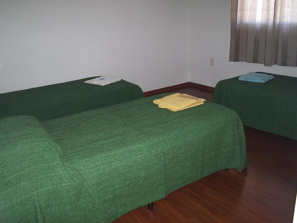 two green beds in a room with wooden floors at Pousada Canto da Maritaca in Resende Costa