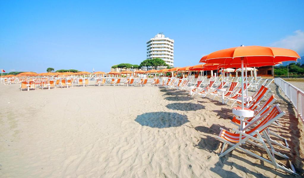 eine Reihe von Stühlen und Sonnenschirmen am Strand in der Unterkunft Torre Del Sole in Terracina