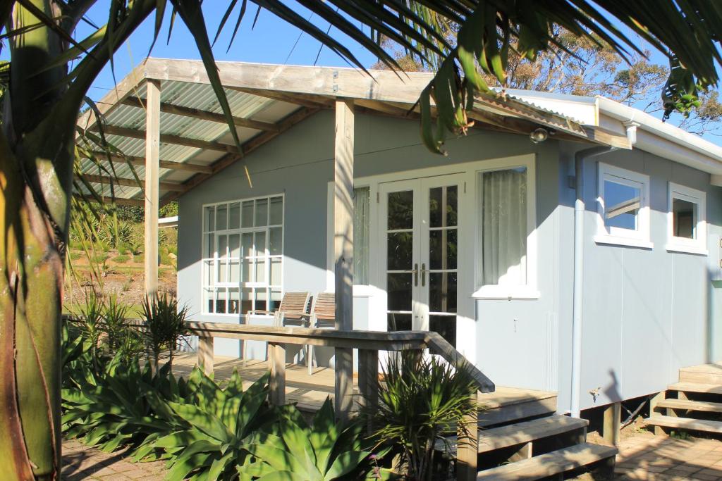 a small house with a porch and a patio at Hot Water Beach Surf Sound Cottage in Hotwater Beach