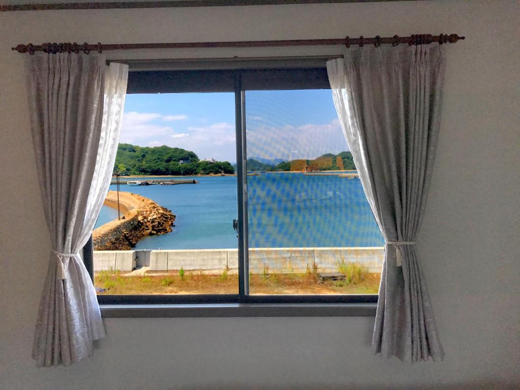 a window with a view of a body of water at Guest House Seaside Namihei in Naoshima
