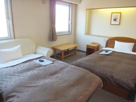 a hotel room with two beds and a window at Hotel Wakasa in Ashikaga