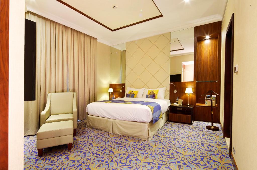 a hotel room with a bed and a chair at Raviz Center Point Hotel in Dubai