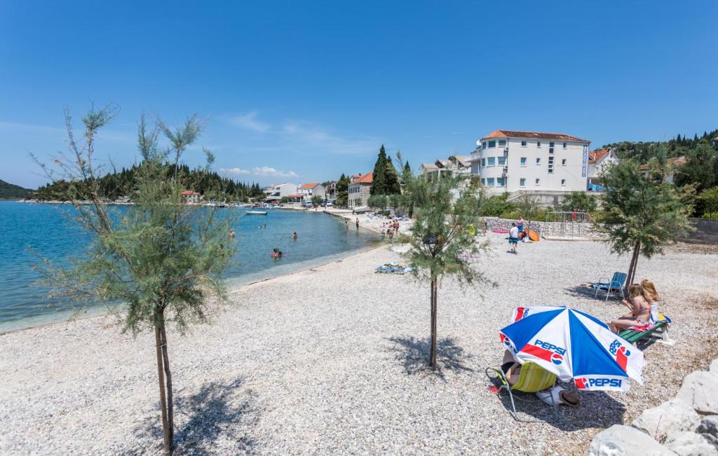 una spiaggia con alberi e un ombrellone blu e bianco di Apartment Lanterna a Blace