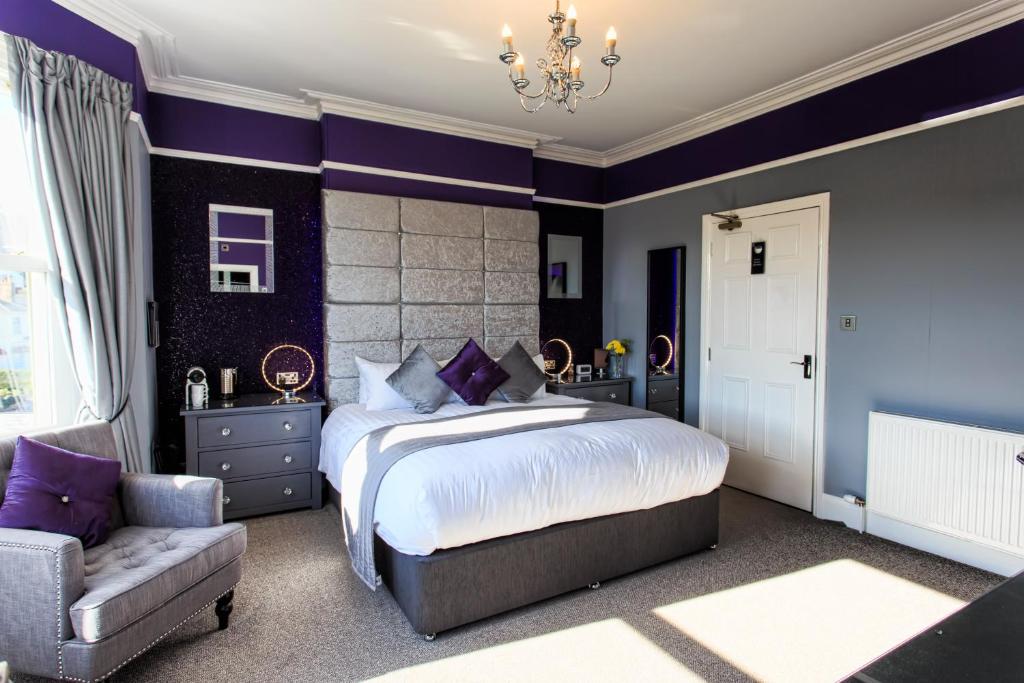 1 dormitorio con paredes moradas, 1 cama y 1 silla en The 25 Boutique B&B - Adults Only, en Torquay