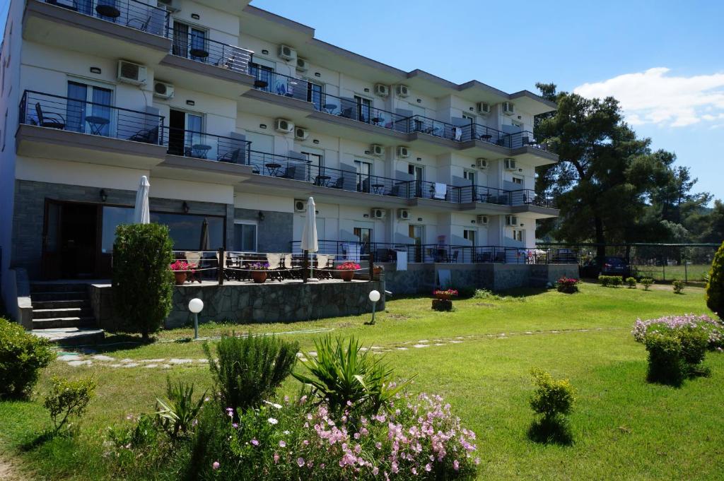 a large building with balconies and flowers in a yard at Vourvourou Hotel in Vourvourou